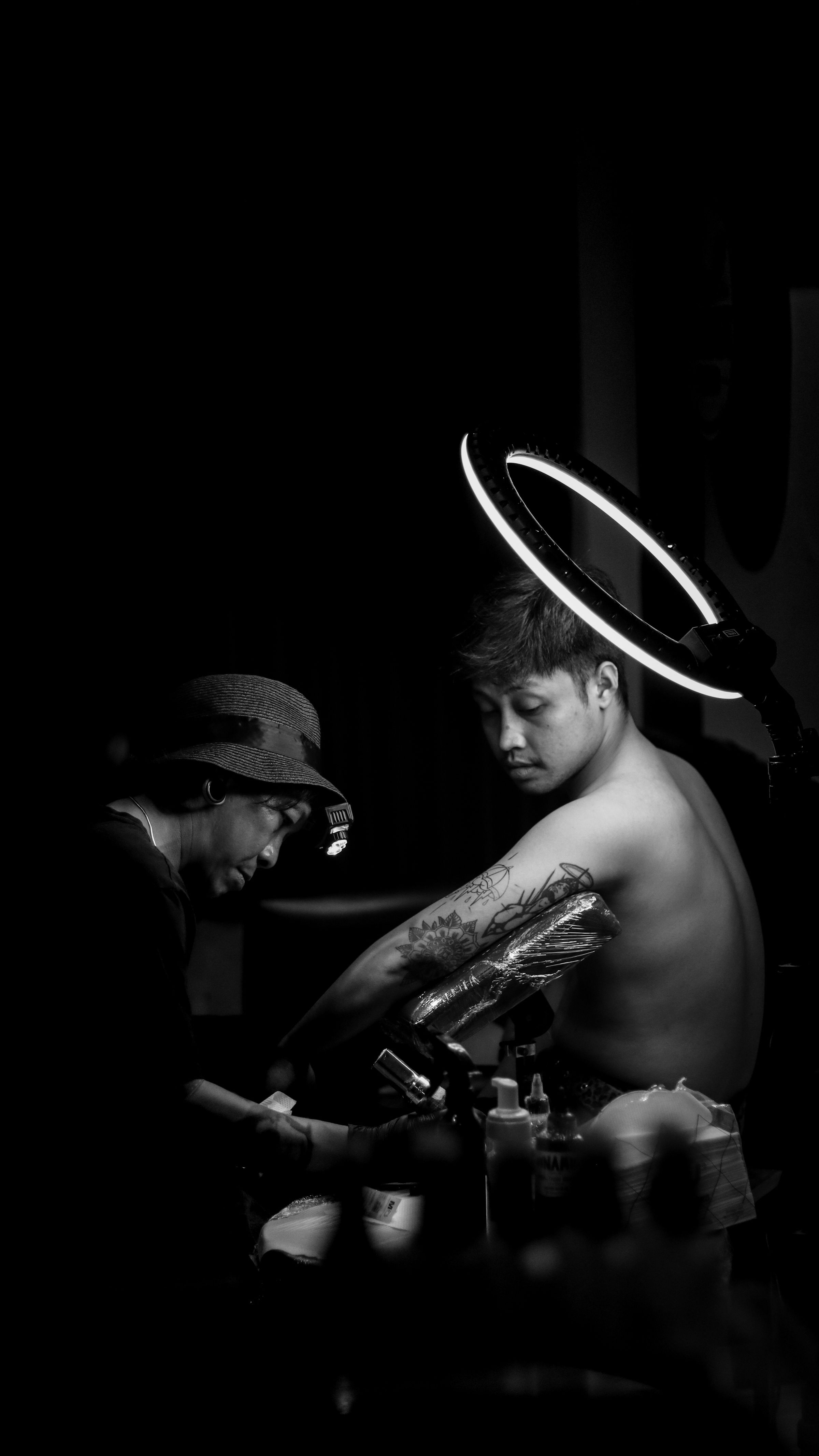 Black-and-white tattoo session under a ring light