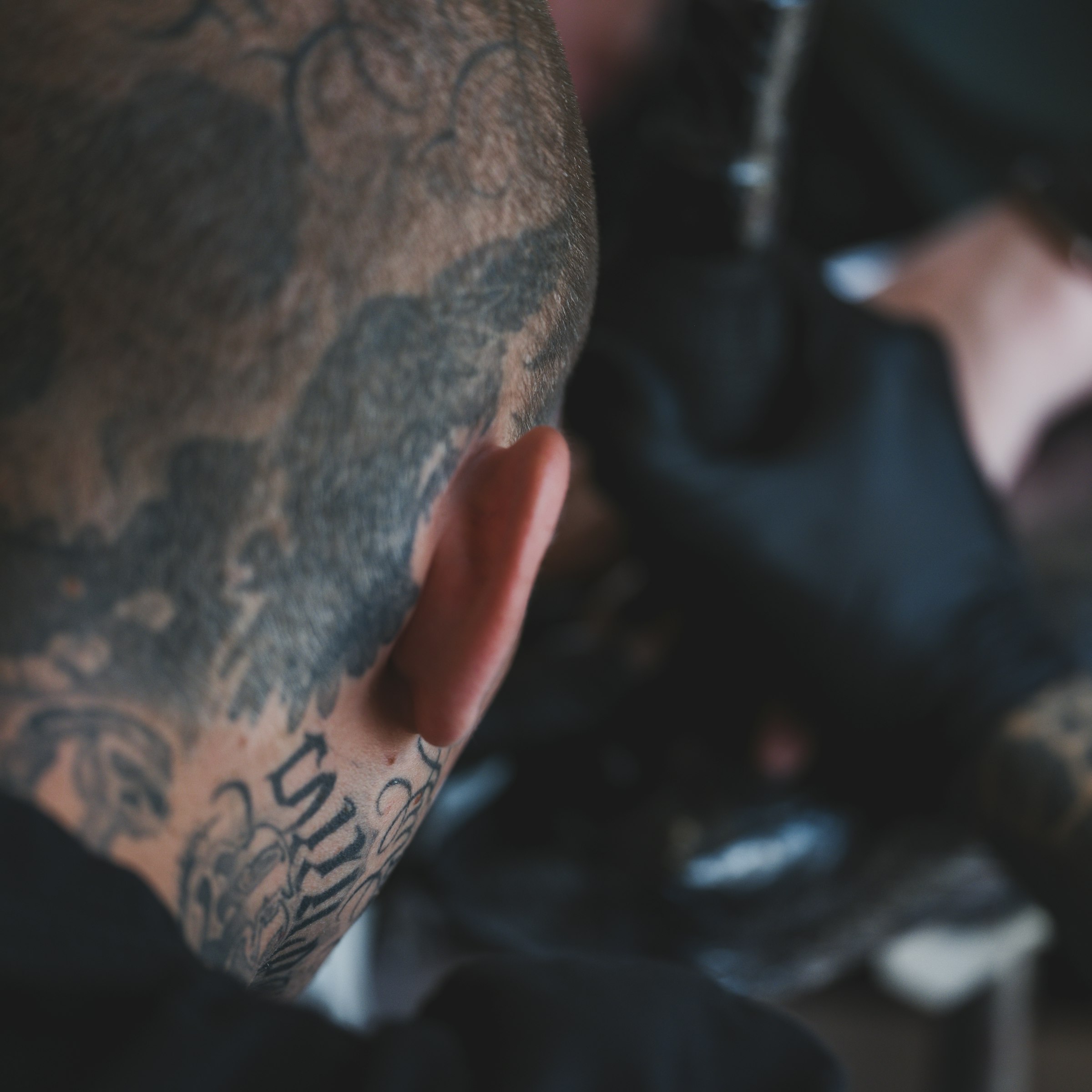 Close-up of custom black-ink tattoos along a neck and scalp