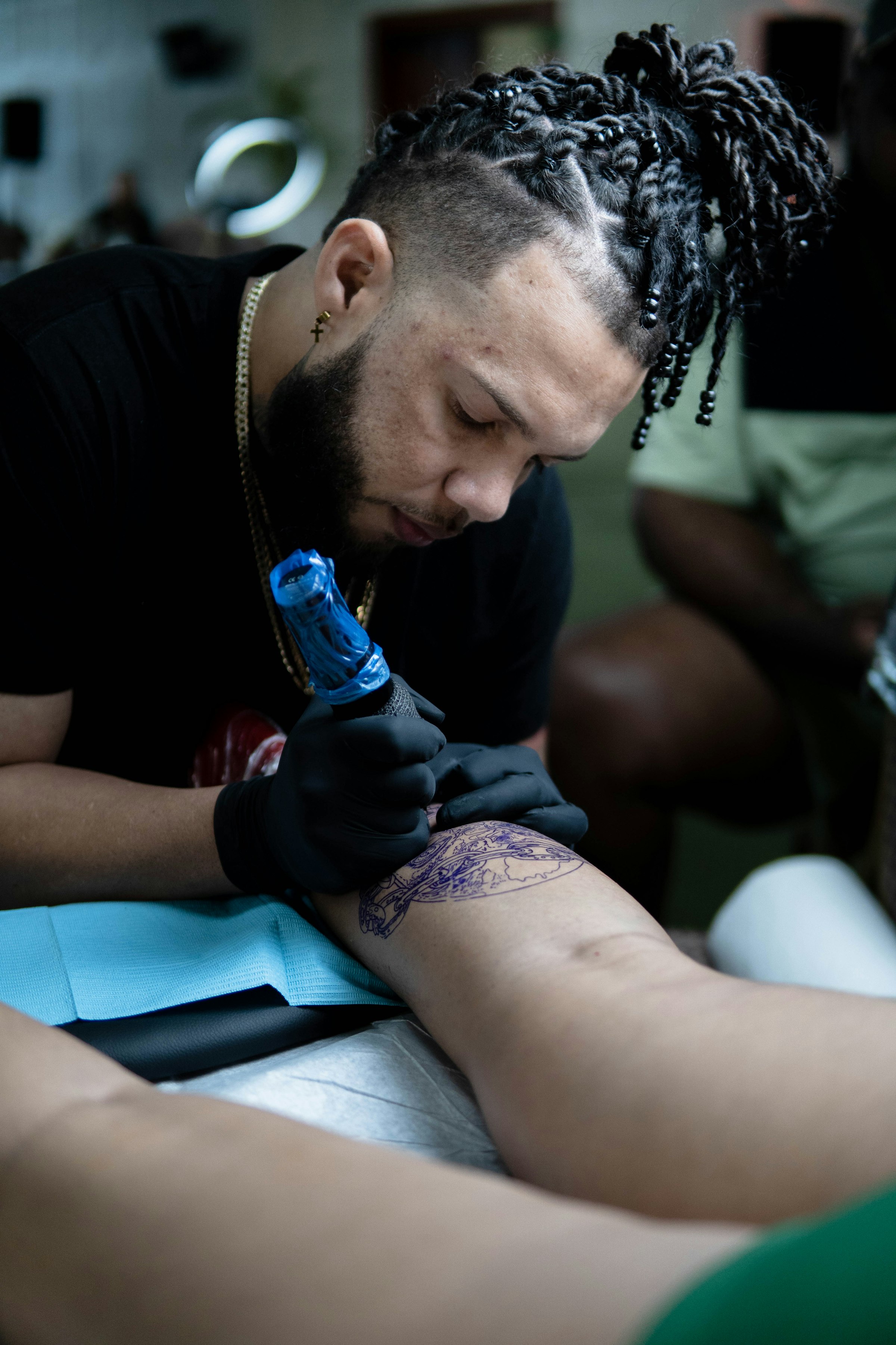 Tattoo artist tracing a stencil on a client’s leg